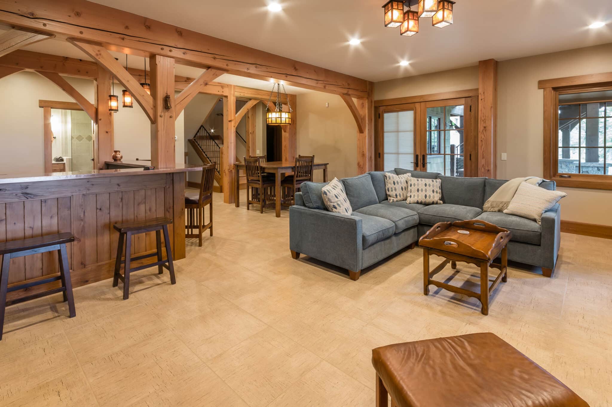 Finished lower level with timber beams, a wet bar and comfortable seating built by Seghi Renovations