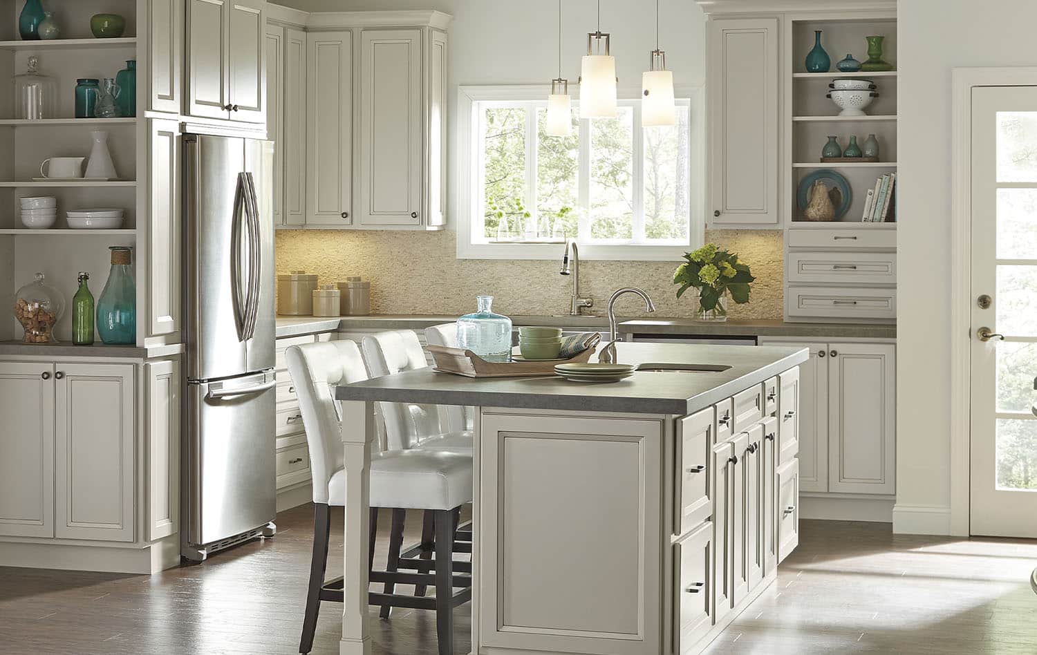 Bright white kitchen remodel with a large island, pendant lights and custom cabinetry by Seghi Renovations in South Lyon, Michigan